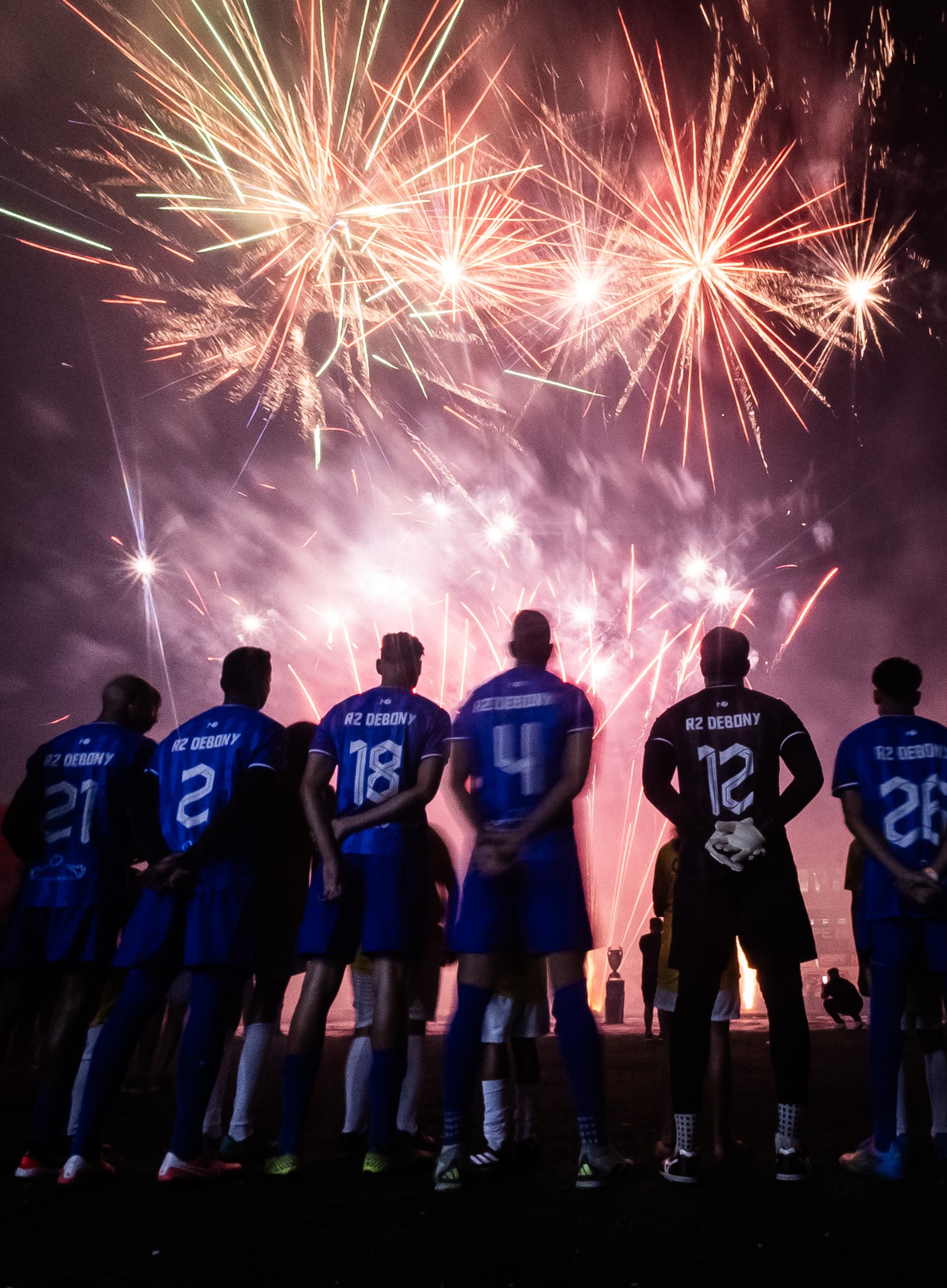 Jogadores vistos de costas sob fogos de artifício