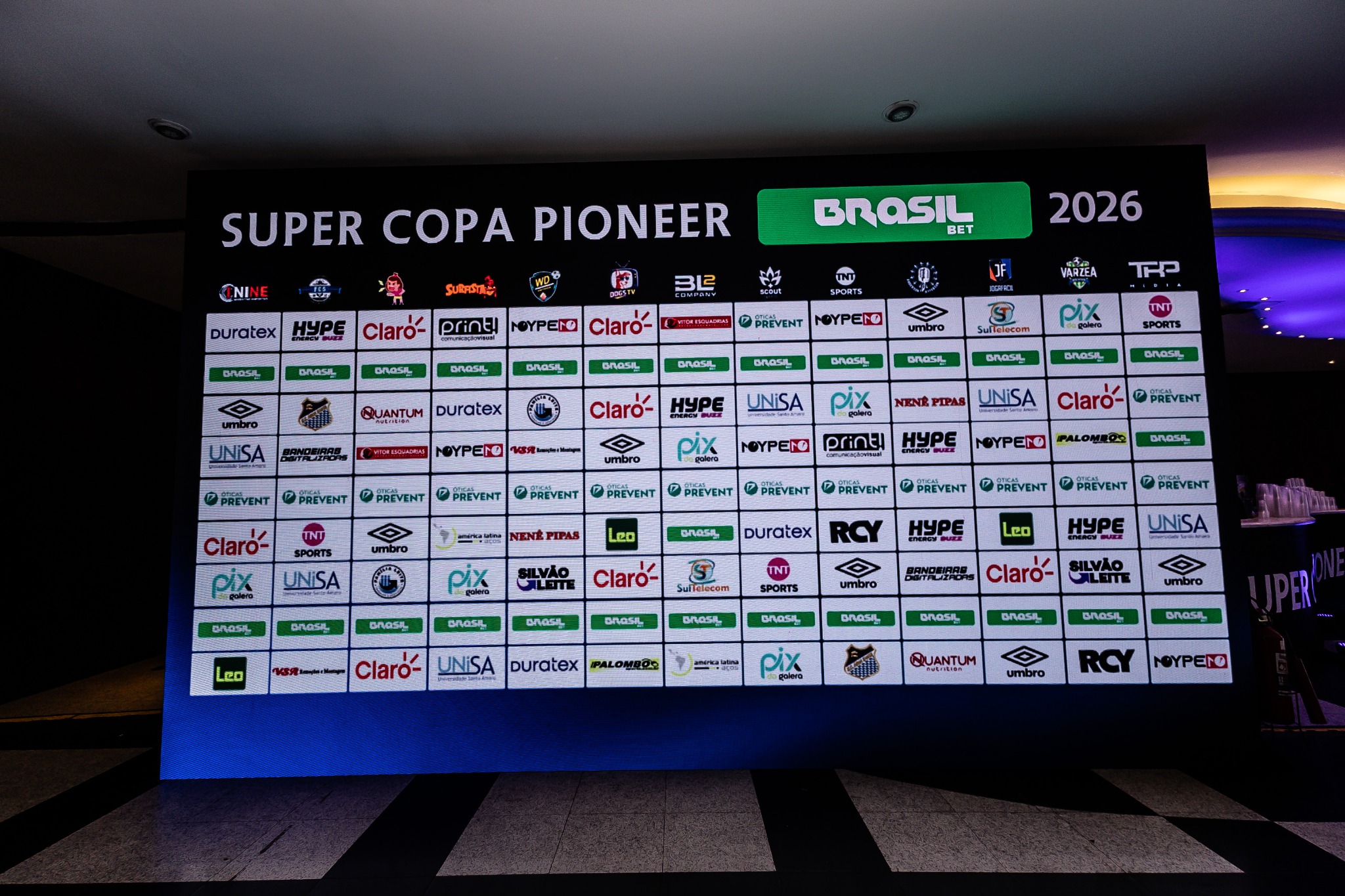 Painel de marcas ao fundo do espaço do Congresso Técnico.