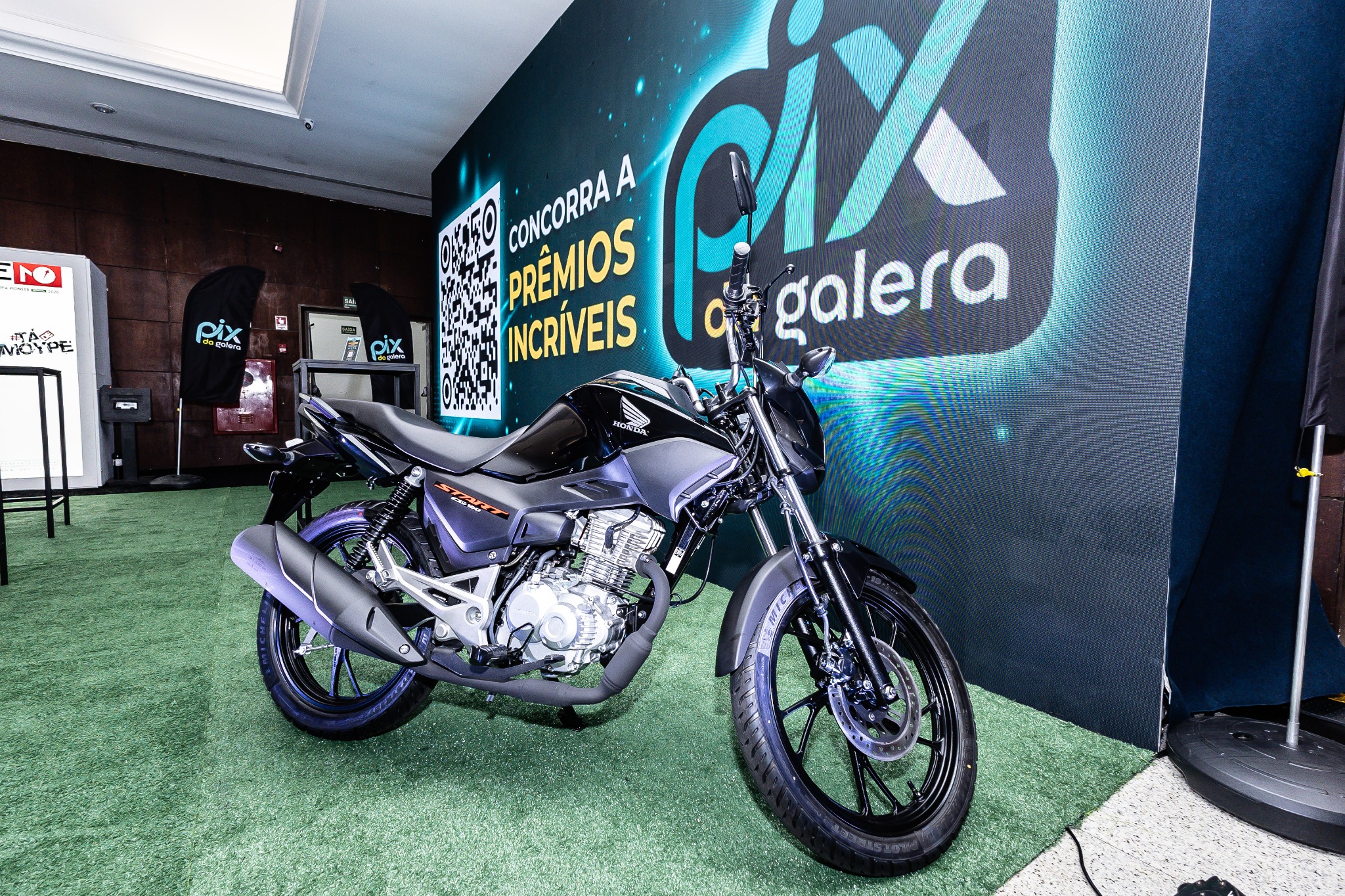 Motocicleta posicionada junto à comunicação visual da PIX DA GALERA.