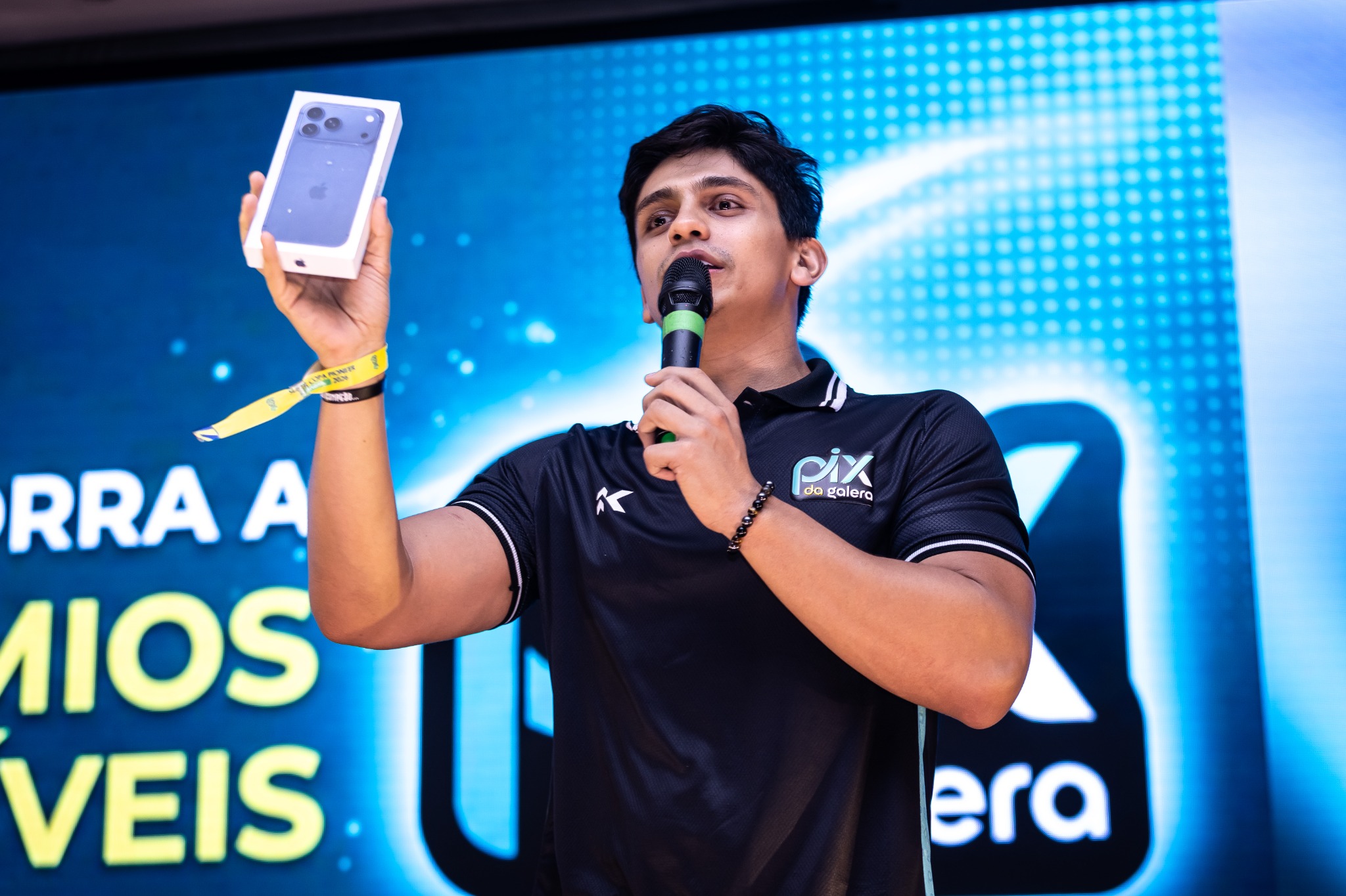 Um apresentador mostra o celular ao público durante a fala no palco.