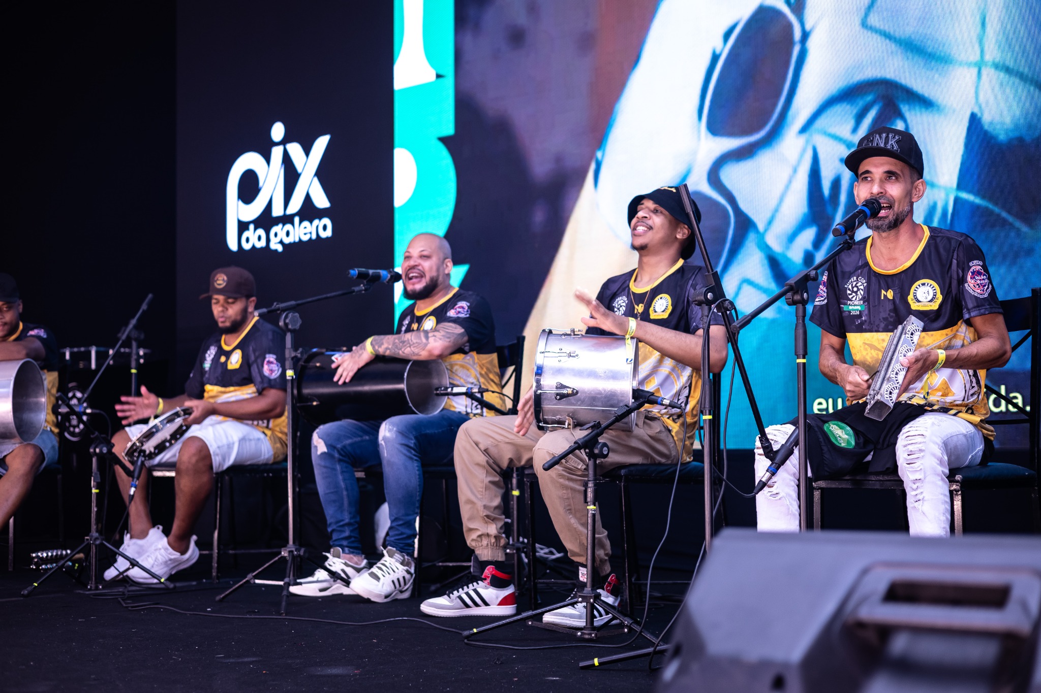 Convidados participam de uma conversa no palco diante do painel PIX DA GALERA.