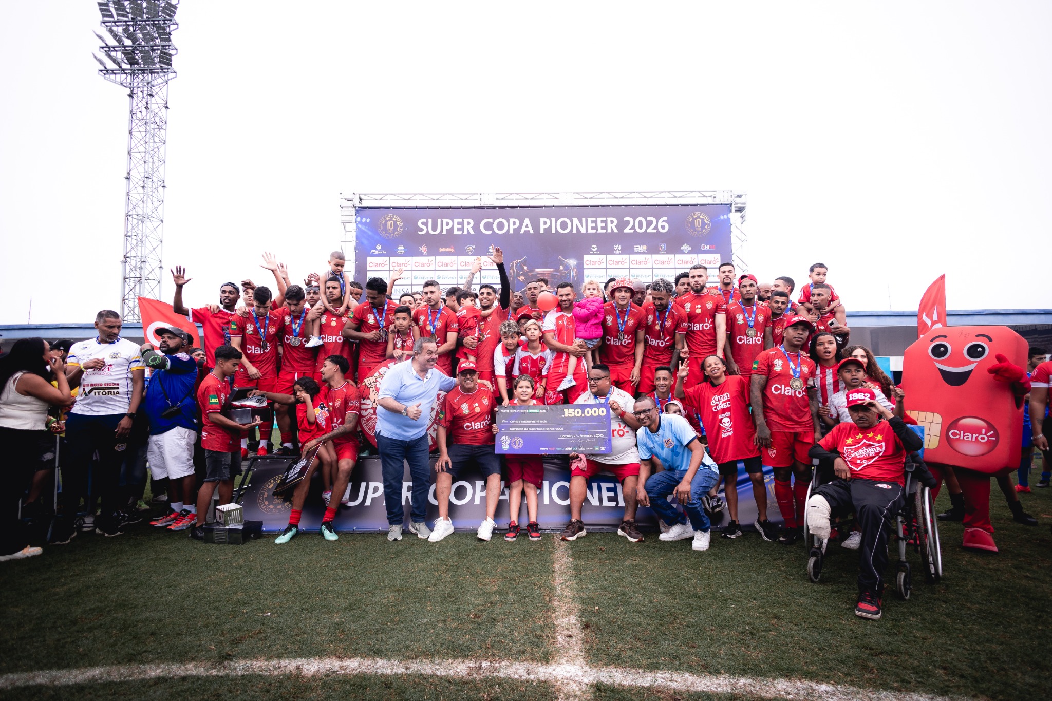 Equipe reunida no gramado com o troféu e a mascote da competição