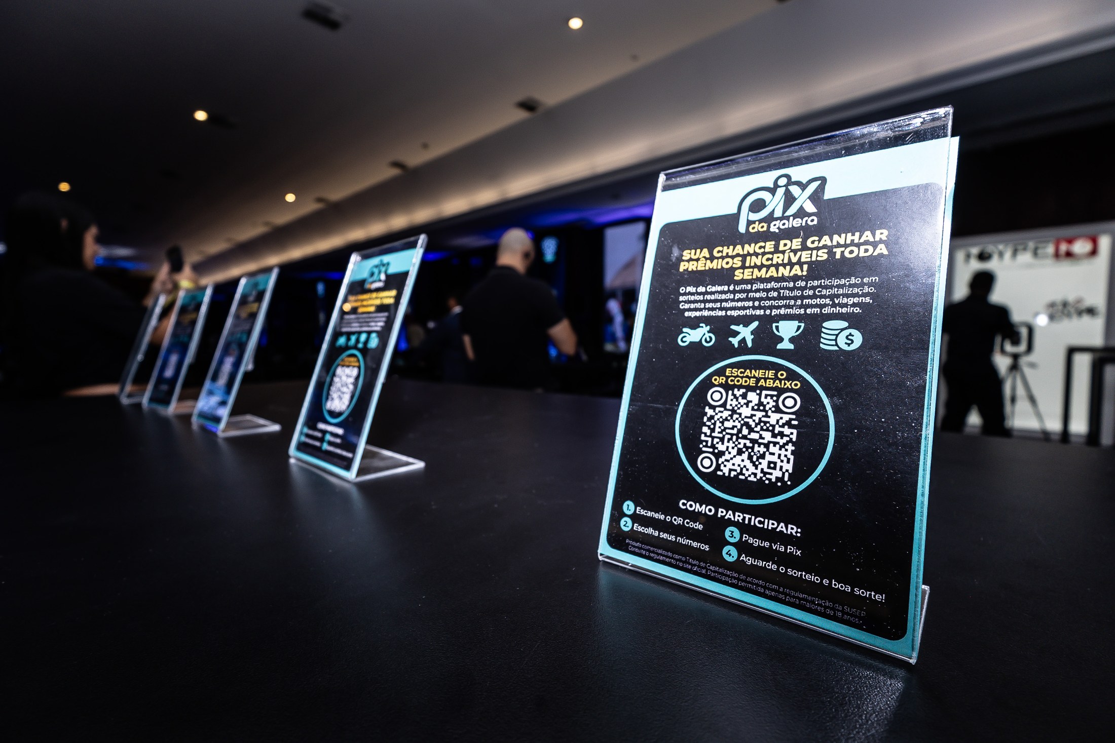 Placa com o logo PIX DA GALERA e QR code junto aos materiais do evento.