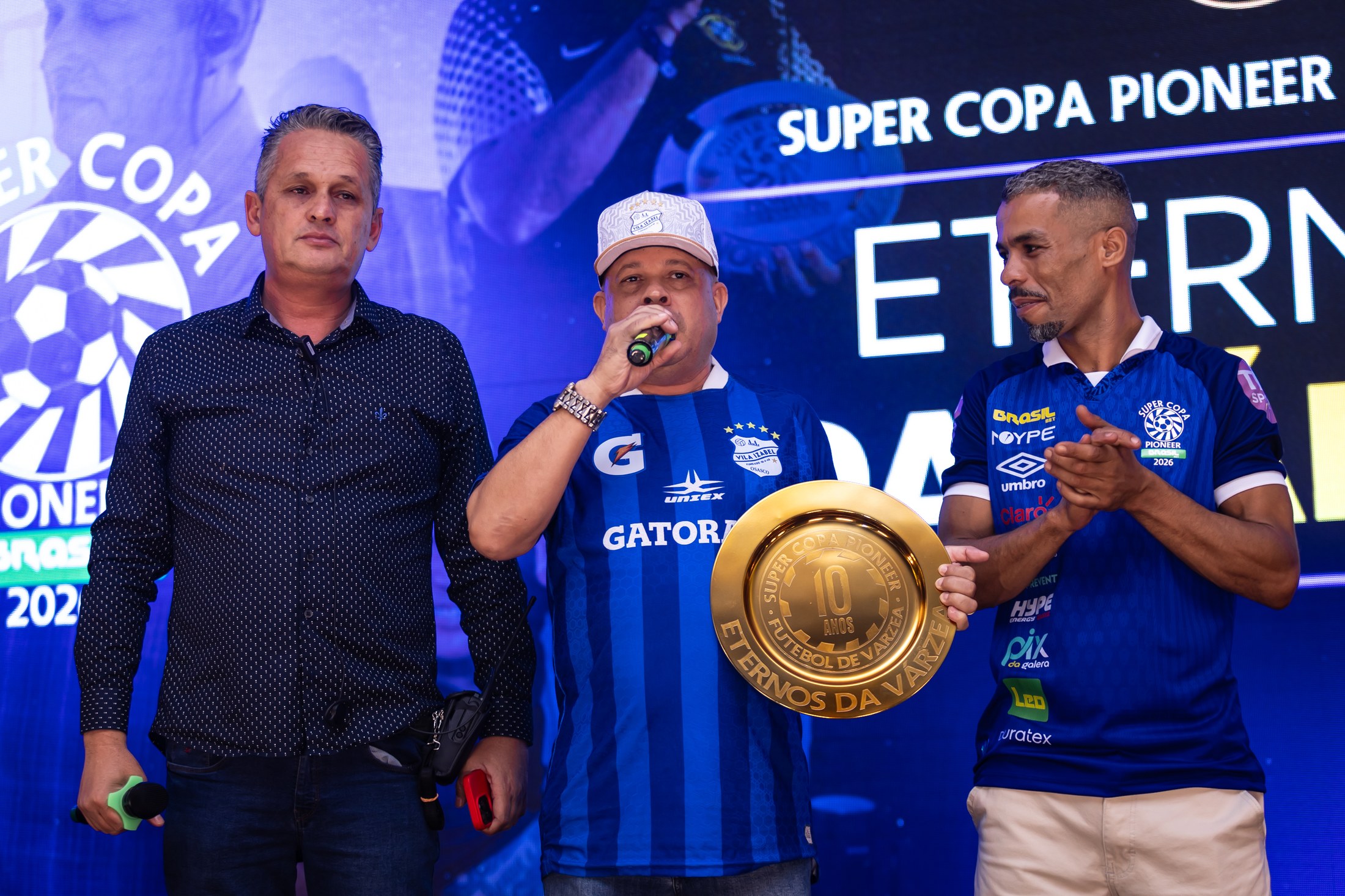 Convidados com troféu diante do backdrop da SCP 2026 que inclui PIX DA GALERA.