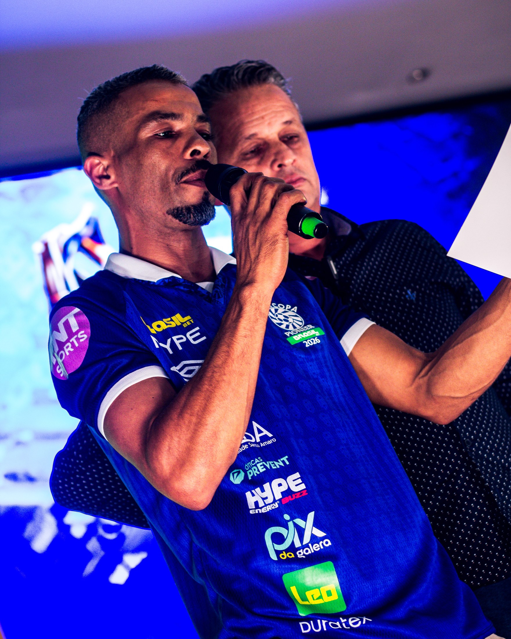 Convidado no palco com camiseta PIX DA GALERA e bola nas mãos.