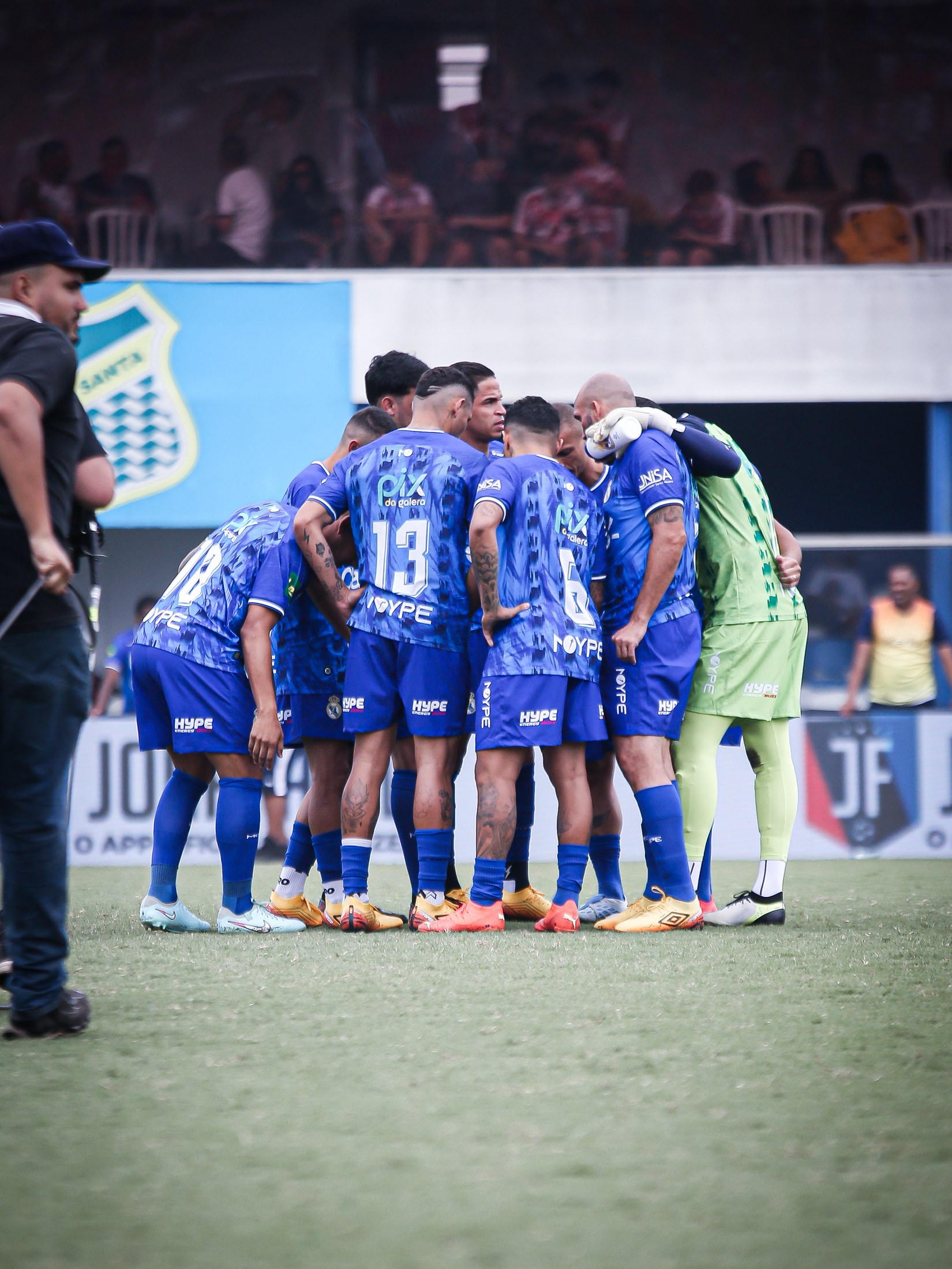 Equipe conversa antes da partida, com o logo PIX DA GALERA visível em uma camisa.