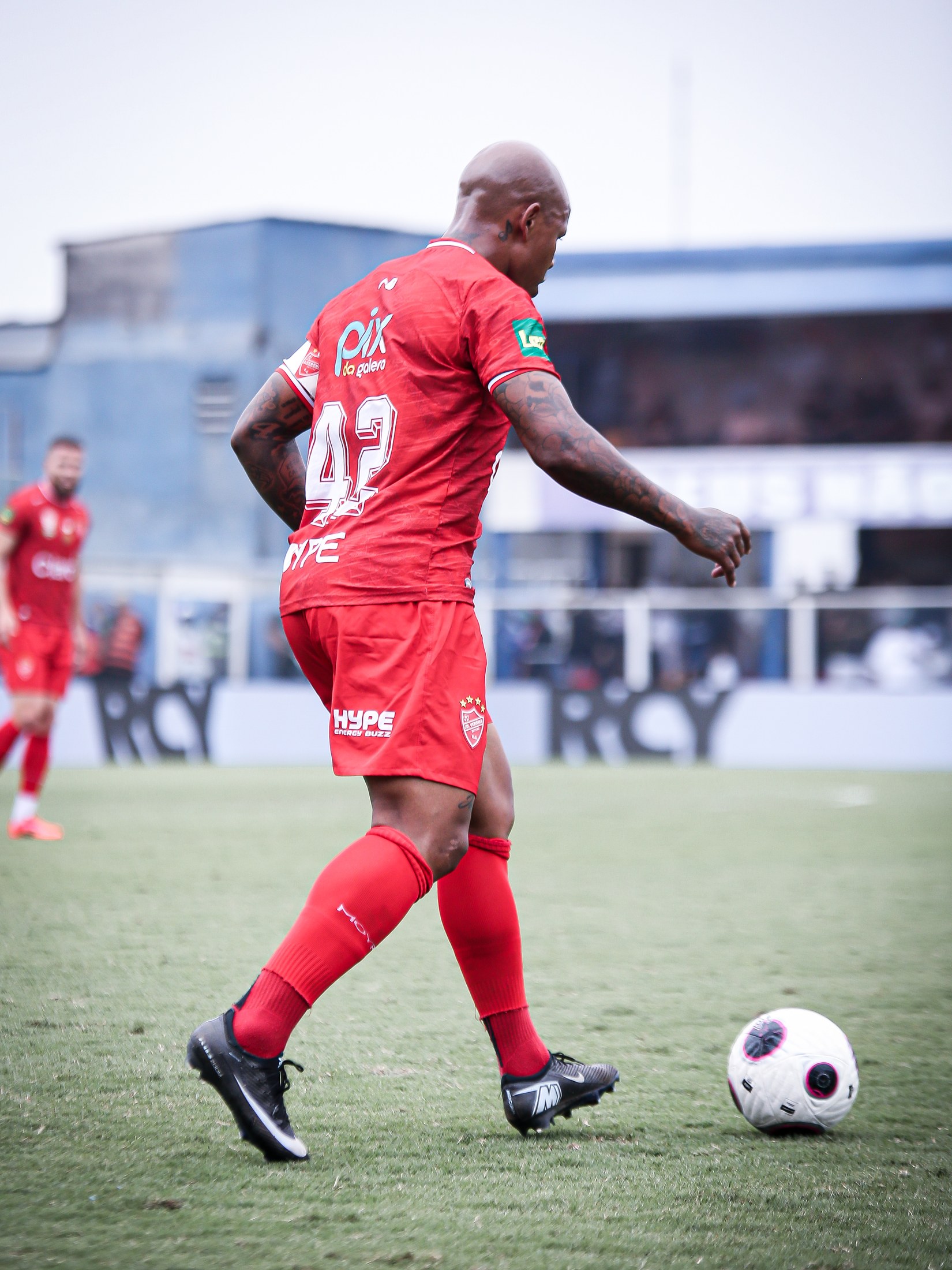 Jogador da equipe vermelha avança com PIX DA GALERA legível no uniforme.