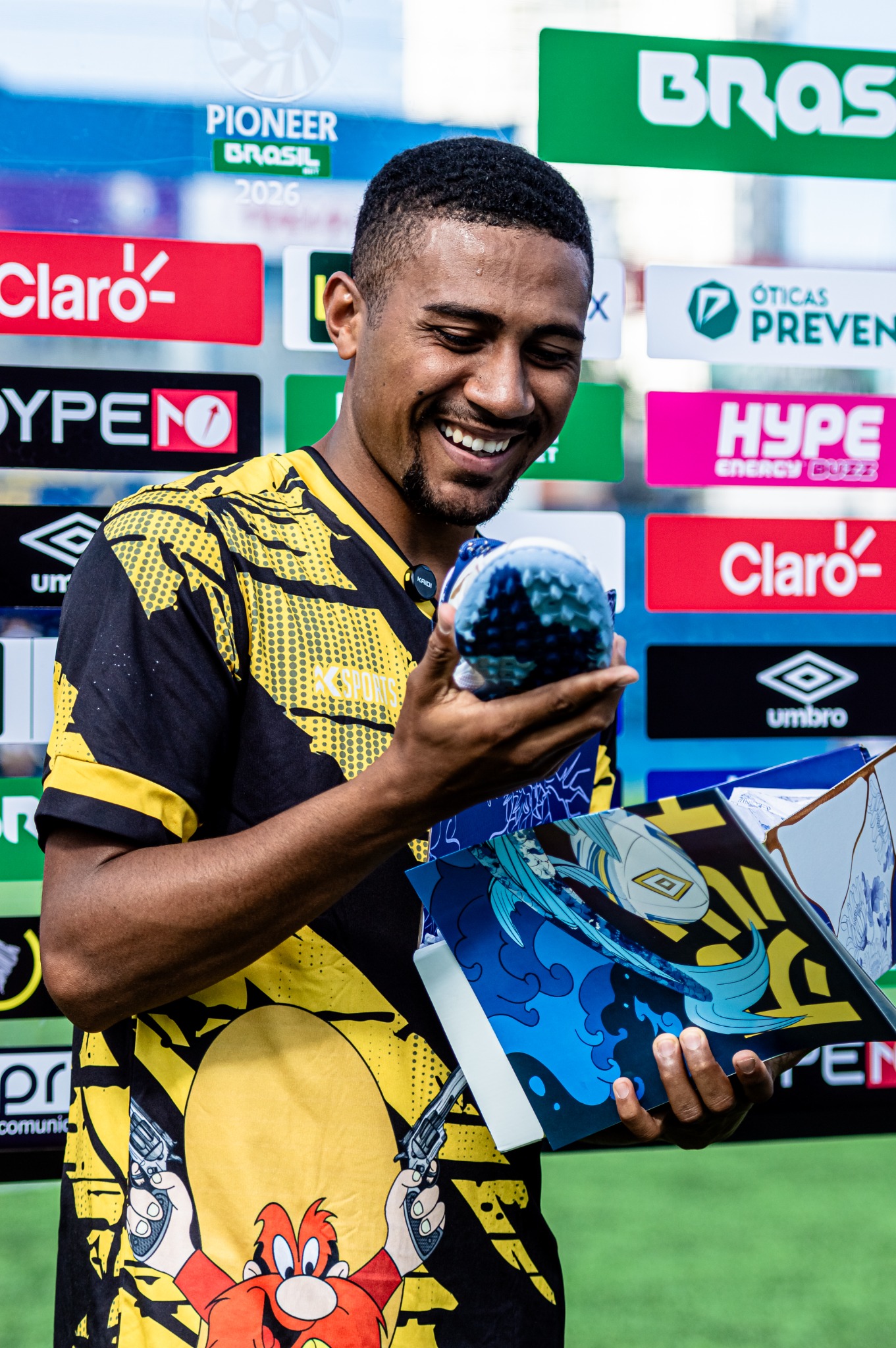 Atleta posa com item de premiação em frente ao painel da competição